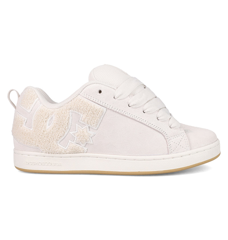 The Women's Court Graffik SD Shoes by DC Shoes are white low-top sneakers with a textured DC logo, white laces, pale beige rubber sole, and a suede upper—offering a simple, clean design for an effortlessly classic look.