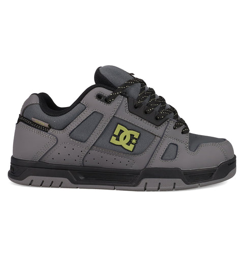 The DC Shoes Men's Stag features a gray upper with black accents, perforated details, black laces with white specks, and a black-and-yellow DC logo. It has a chunky silhouette, durable cupsole, and a black and gray sole for true skate style.