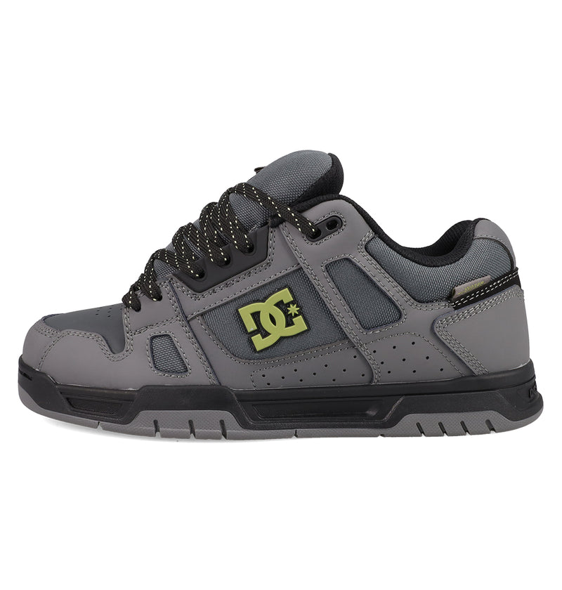 The DC Shoes Men's Stag Shoes feature a gray upper with black laces, black sole, yellow DC logo, padded tongue and collar, perforated details for breathability, and a durable cupsole inspired by skate culture.