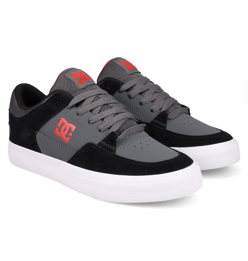 The Men's Onyx Shoes by DC Shoes feature a minimal gray and black design with white soles, gray laces, mesh tongue, and red DC logos on the side and tongue.