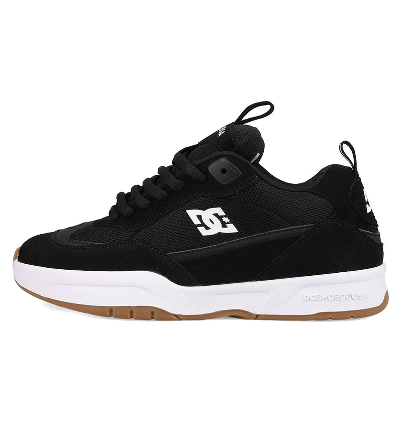 The Men's JS-2 Shanahan Pro Skate Shoes by DC Shoes feature a black upper with mesh and suede panels, a white side logo, white midsole, brown rubber outsole, black laces, pull tab on the tongue, and highlight DC heritage.