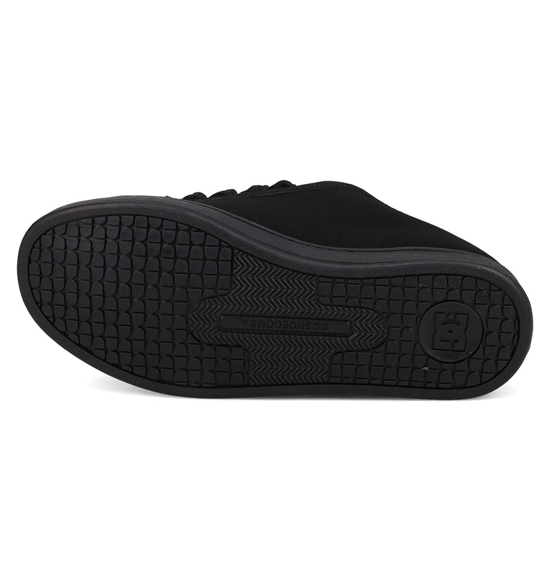 The image shows the black rubber sole of the Women’s Court Graffik Day Of The Dead sneaker by DC Shoes, featuring a textured tread pattern and a circular logo near the heel area.