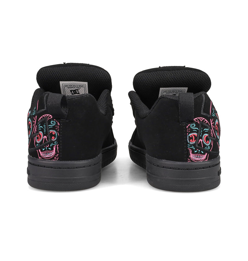 A pair of DC Shoes Kids’ Court Graffik Day Of The Dead sneakers, shown from the back, featuring colorful embroidered sugar skull designs on the heels. These black sneakers are inspired by Día de los Muertos and are part of the exclusive Day of the Dead Collection from DC Shoes.