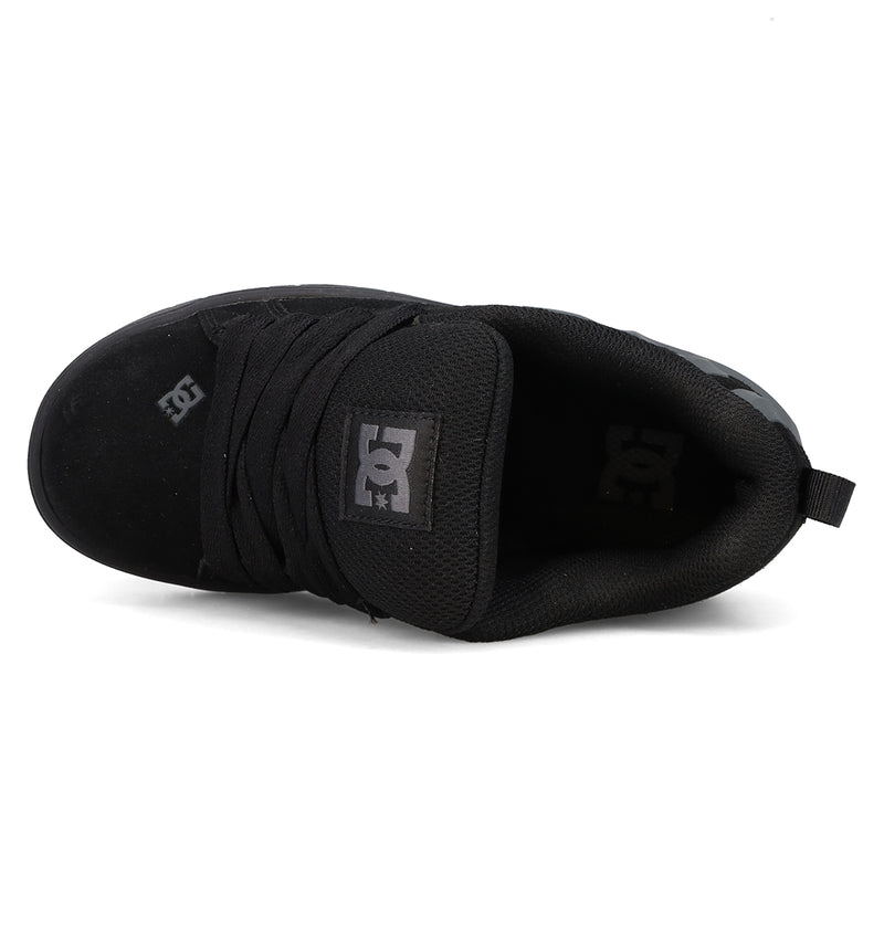 Top view of a black DC Shoes Kids’ Court Graffik Beveled Special Edition skate shoe, featuring black laces and prominent white DC branding on the tongue and side. The shoe showcases a puffy silhouette, low-top design, and a convenient pull tab on the heel.