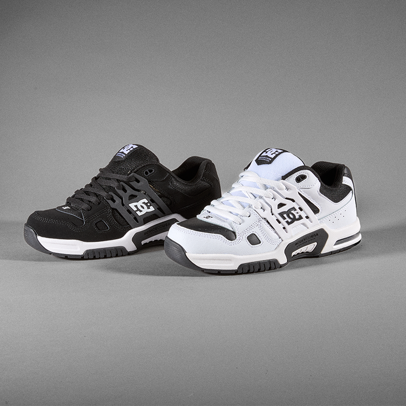 Two DC sneakers shown on a neutral gray studio background, one in black and one in white, both featuring the DC logo on the side and tongue.