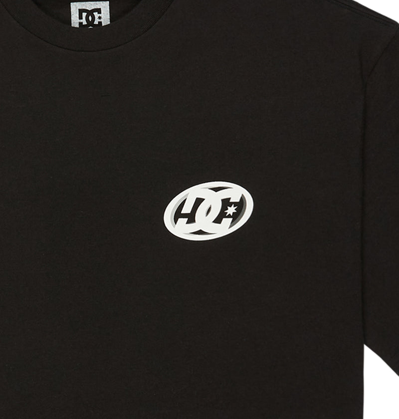 Close-up of the DC Shoes Fast Bubble Hss black T-shirt, showing a small white logo with a star inside an oval on the left chest. The collar and part of the label are also visible.