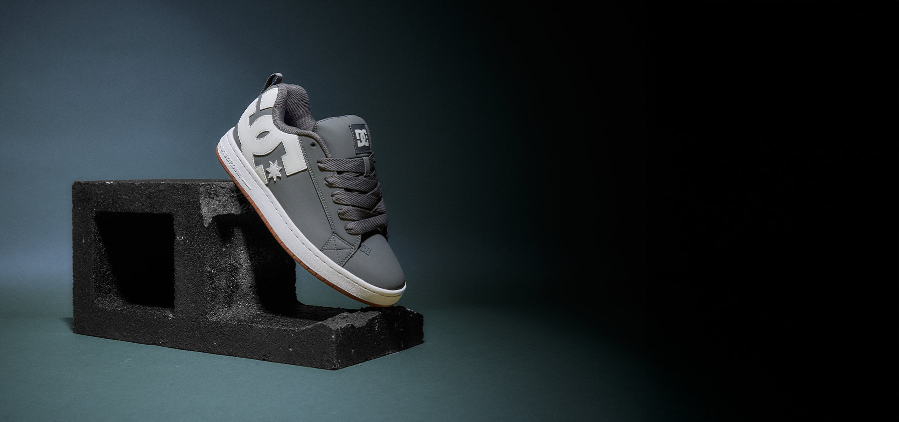 Gray sneaker on a black block against a dark background