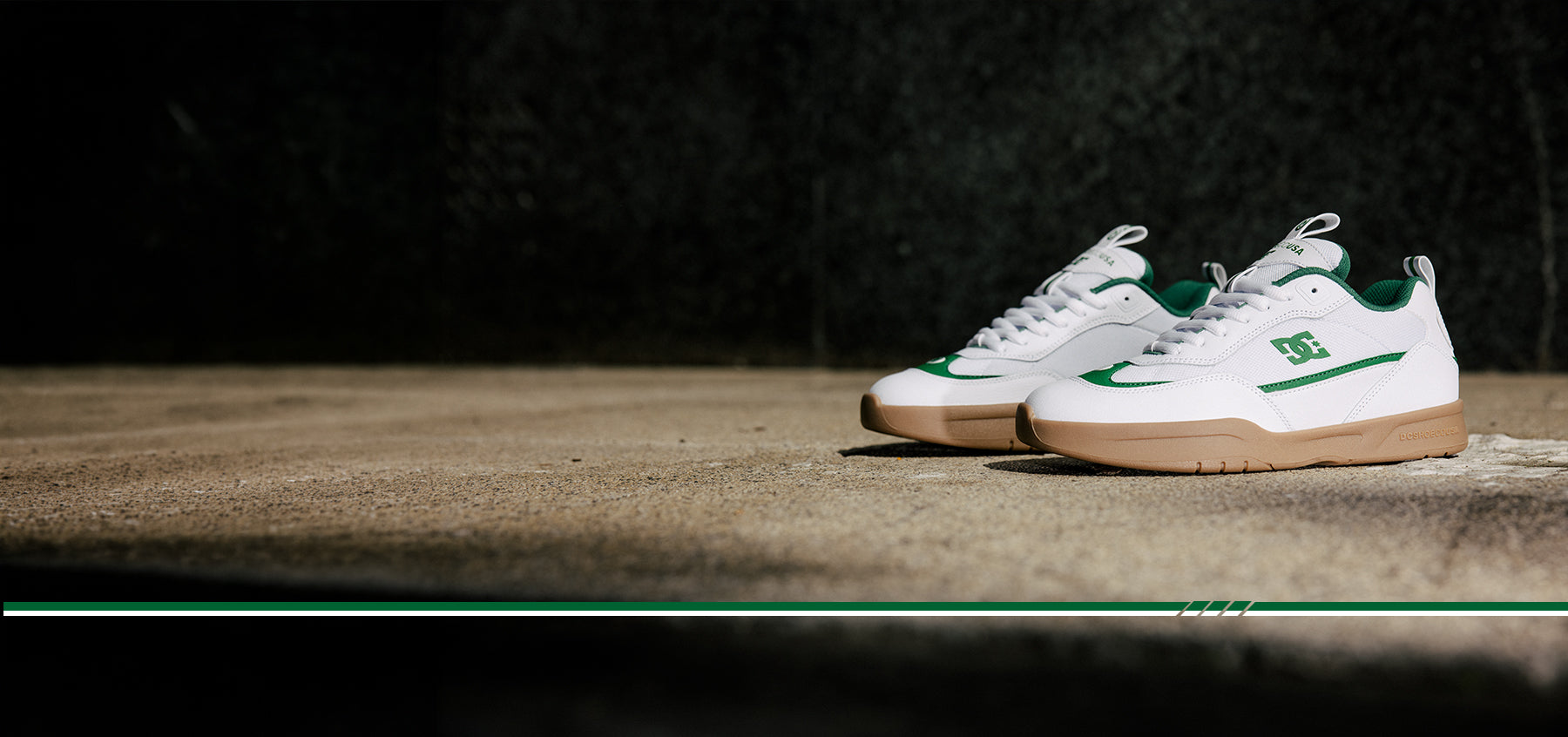 White sneakers with green accents on a dark background and wood flooring