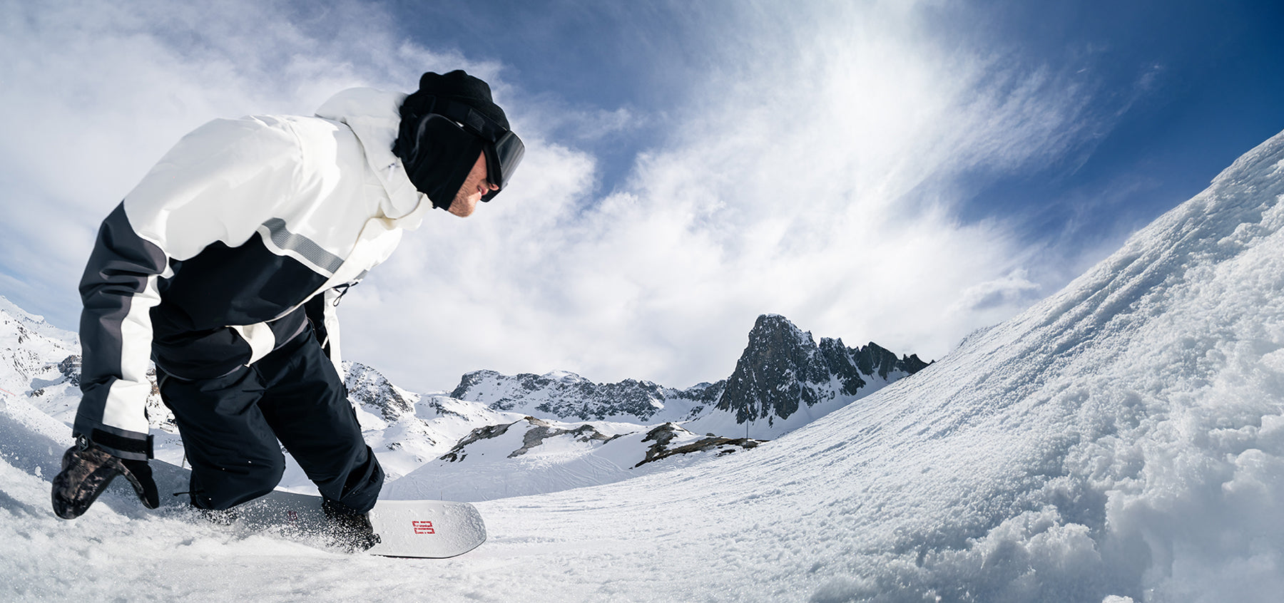 Person in a reflective snow suit snowboarding on a snowy mountain.