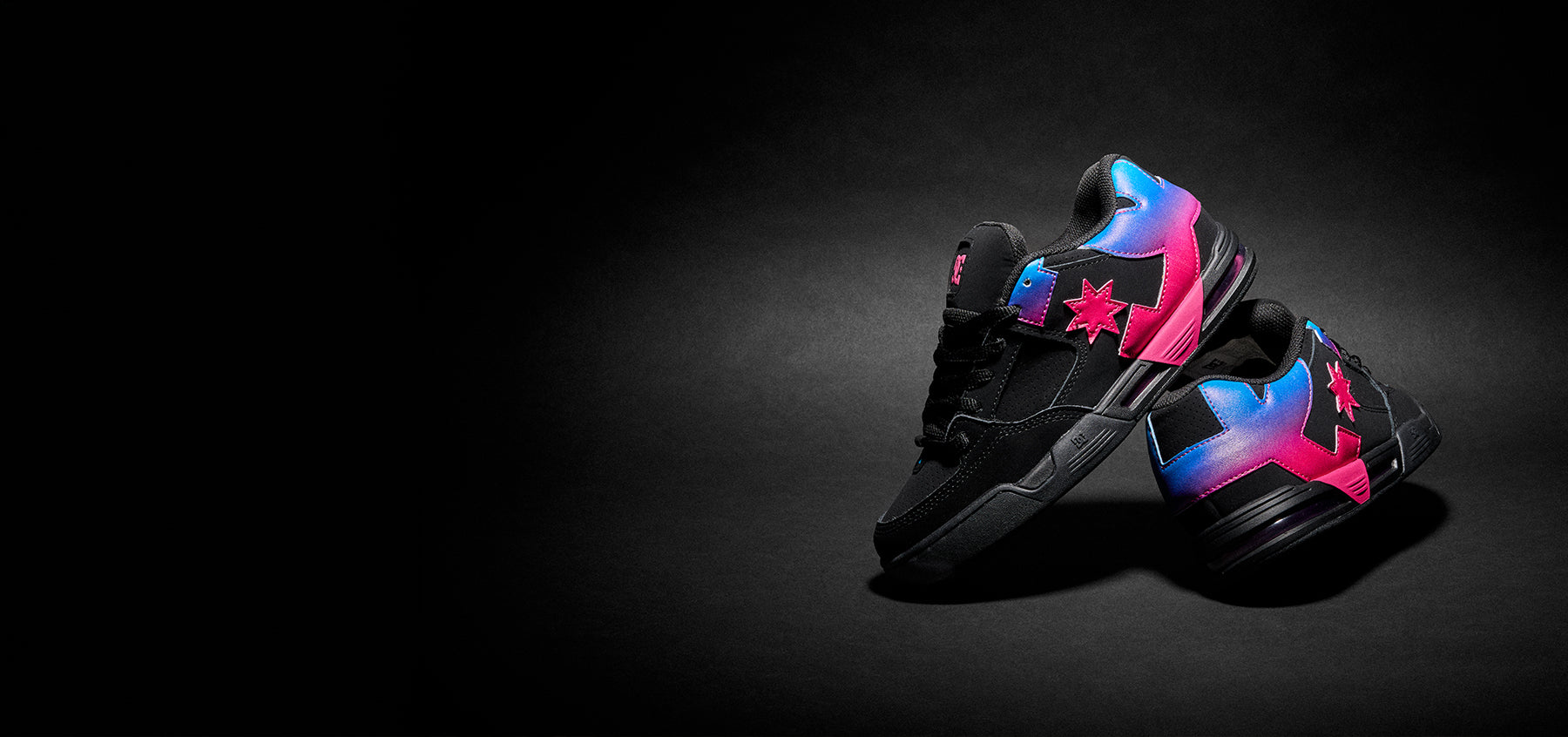 Black sneakers with colorful pink & blue gradient logo on a dark background