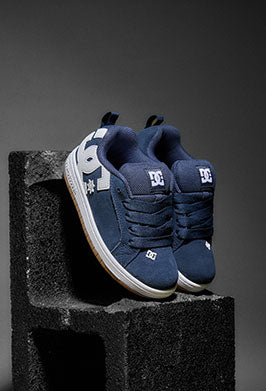 Pair of blue DC shoes on a black block with a gray background