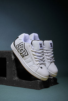 White sneakers with a DC logo on a dark background