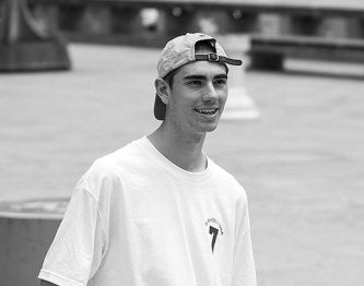 Black and white photo of a person wearing a cap and t-shirt with a logo.