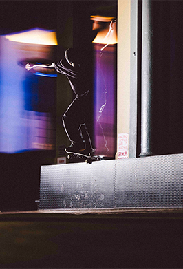 Person skateboarding reflected in a window with colorful lights