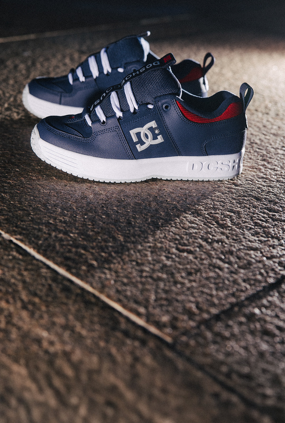 Pair of navy blue DC sneakers on a textured surface