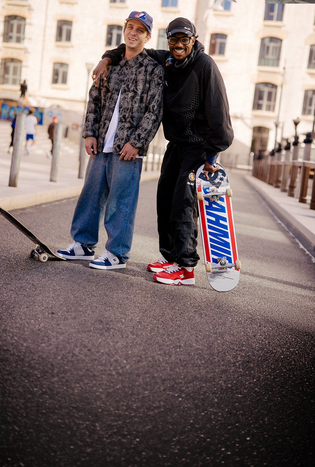 Two skateboarders posing on a street with their boards.