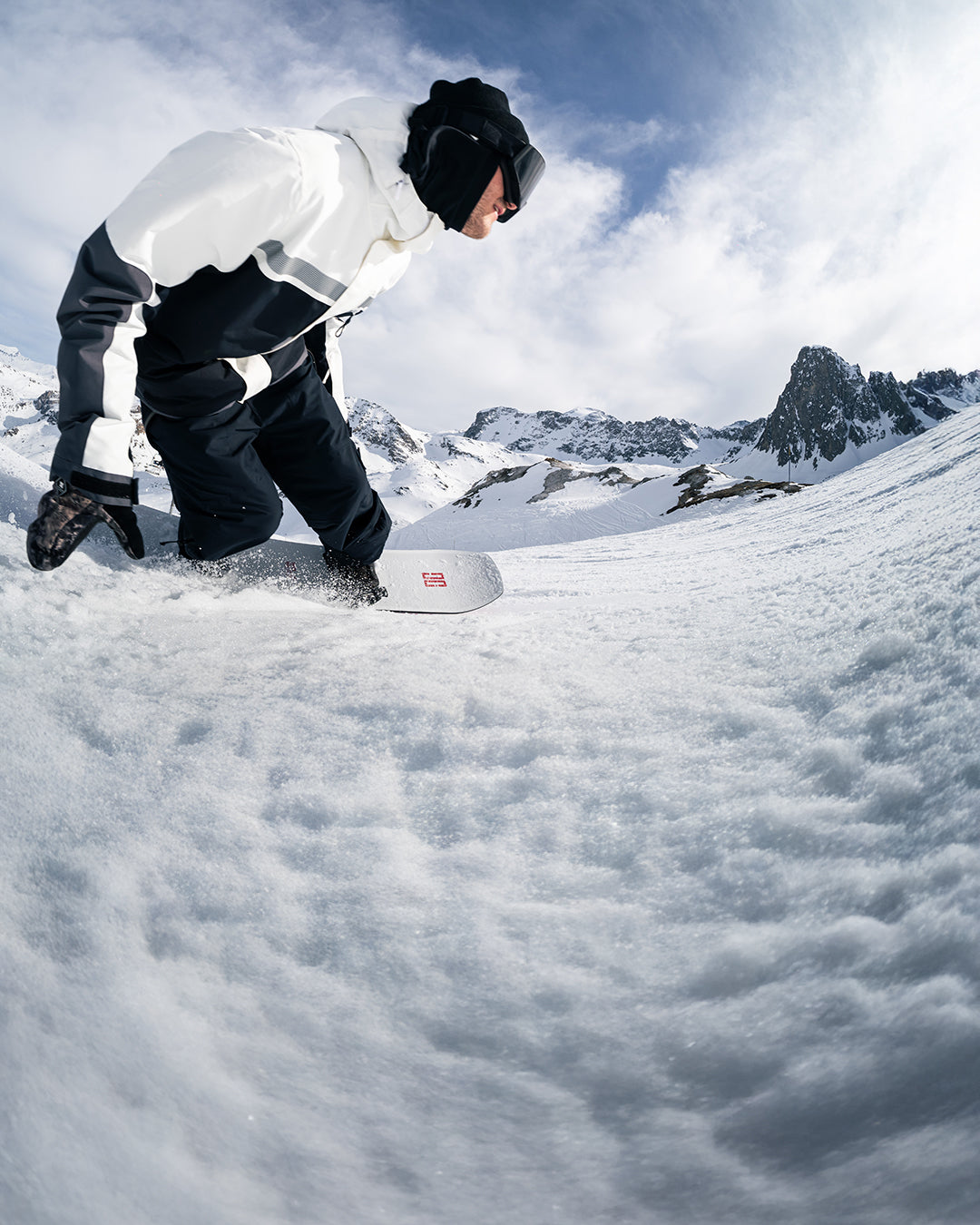 Person in a reflective snow suit snowboarding on a snowy mountain.