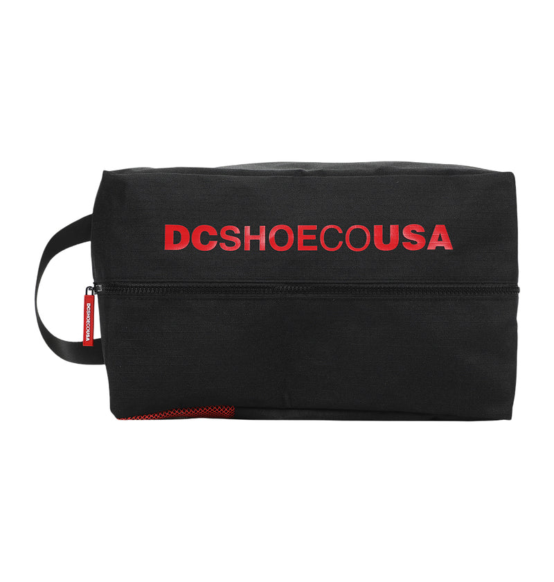 The DC Runner Shoe Bag by DC Shoes is a black rectangular pouch with a side handle, bold red "DCSHOECOUSA" text on the front, and a horizontal zipper.