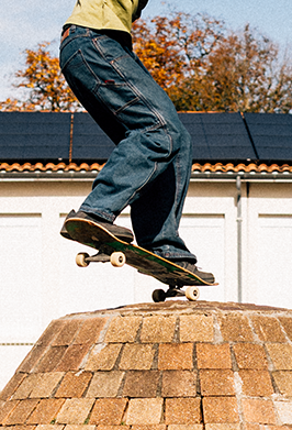 Person skateboarding on a roof with trees and building in the background