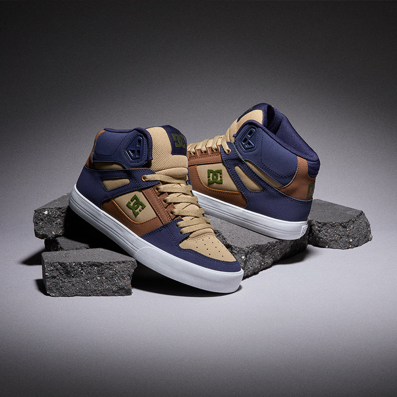 Brown, blue, and tan Dc shoes on a grey background