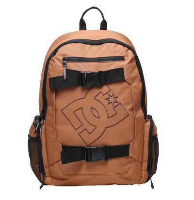 A brown backpack with black straps, front buckles, mesh side pockets, and a large DC Shoes logo printed on the front. The bag has a top handle and a front zippered pocket.
