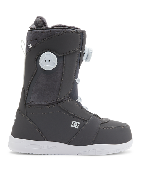 The DC Shoes Lotus snowboard boot features a dark gray design with a white sole, white laces, and a round white BOA dial on the side. The DC Shoes logo appears near the heel and ankle.