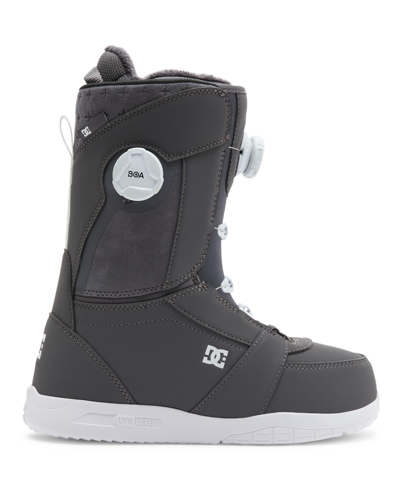 The DC Shoes Lotus snowboard boot features a dark gray design with a white sole, white laces, and a round white BOA dial on the side. The DC Shoes logo appears near the heel and ankle.