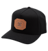The Men's Reynotts Cap by DC Shoes is a black skate cap with a curved brim, featuring a brown leather front patch debossed with “DC Shoe Company, Est. 1994, Quality Goods.”.