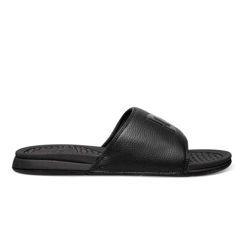 The DC Shoes Men's Bolsa Slides feature a textured footbed and wide black strap, shown from the side against a white background—ideal footwear for relaxing after a skate session.