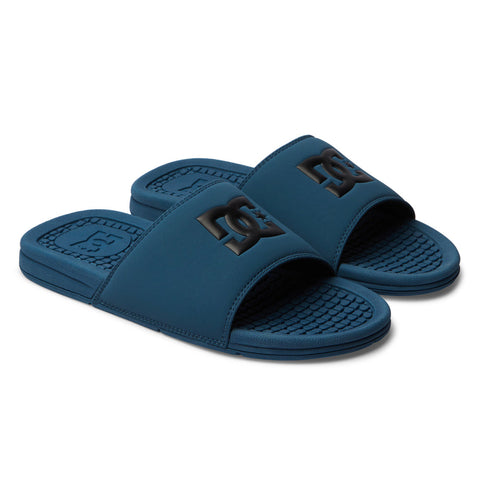 The Men's Bolsa Slides from DC Shoes feature blue wide straps with a raised black DC logo and textured footbeds, offering a sporty, casual style perfect for relaxing after skating.