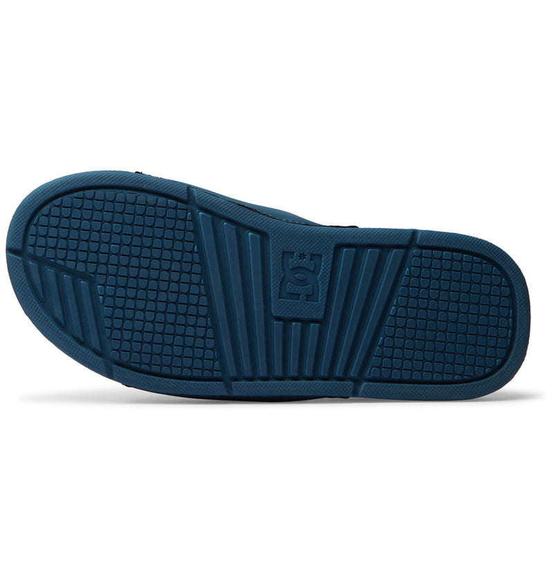 The image shows the sole of the Men's Bolsa Slides by DC Shoes, featuring a blue textured grip pattern and embossed DC Shoes logo—perfect for slipping on after a skate session.