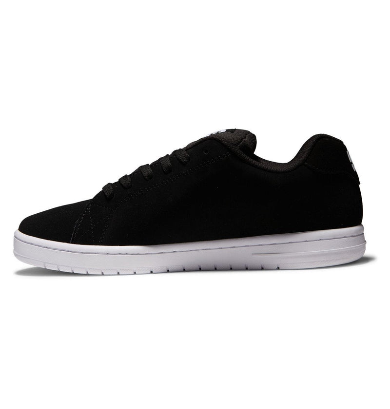 A side view of the Men's Gaveler Shoes by DC Shoes displays a black low-top sneaker with a white sole, black laces, stitching accents, and a minimalist leather upper against a white background for casual style.