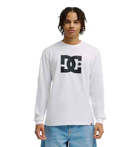 A person in the Men's DC Star Tee by DC Shoes—white with bold black DC graphics—stands against a plain white background, paired with light blue jeans. Ideal for casual hangouts or skate sessions.