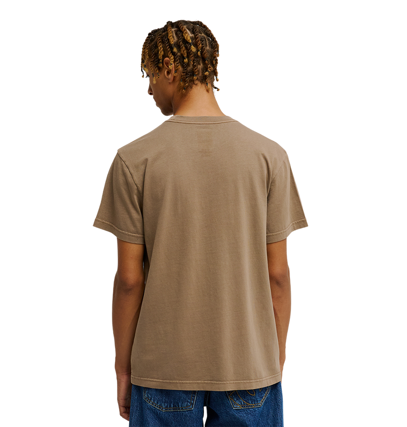 A person with short, twisted hair is shown from the back against a plain white background, wearing the Men's DC Star Pigment Dye Tee by DC Shoes and blue jeans.