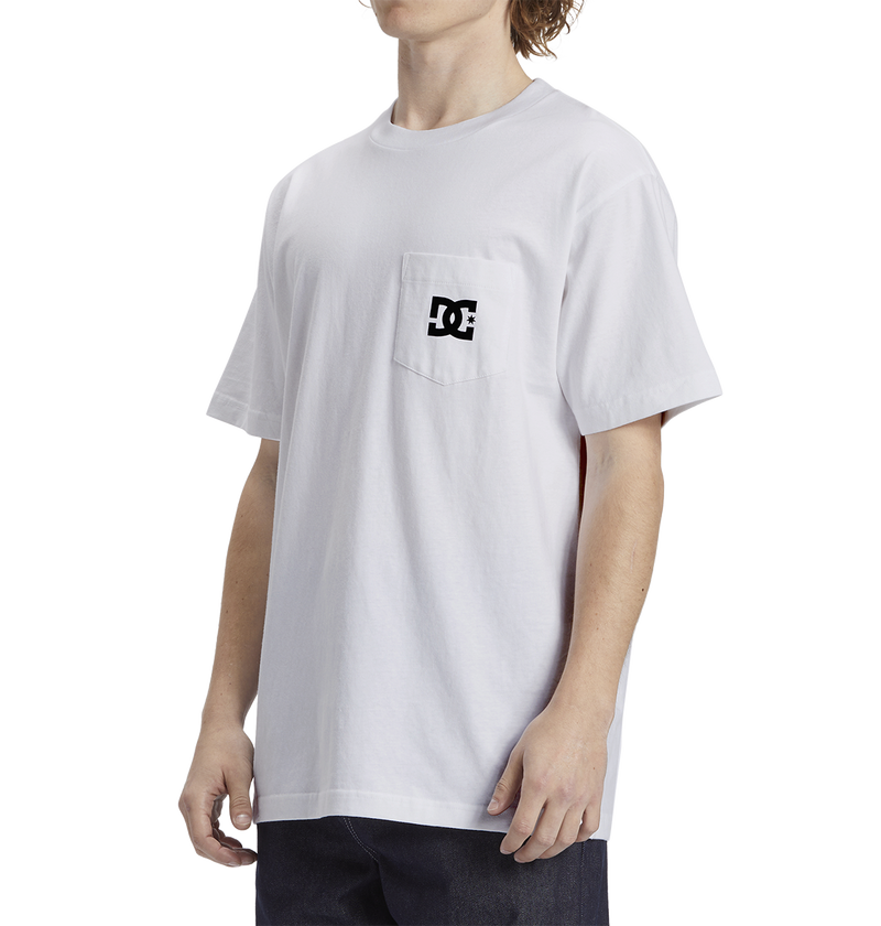 A man wears the Men's DC Star Pocket Tee by DC Shoes, a soft cotton white skate shirt with a small black logo on the chest pocket, relaxed fit, paired with dark pants and set against a plain white background.