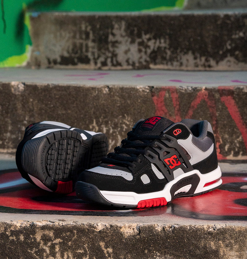 Black and white sneakers with red accents on a concrete surface with graffiti.