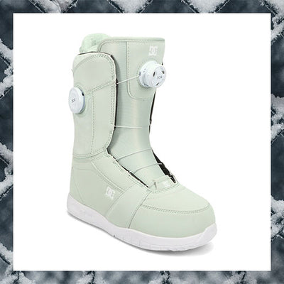 Light green snowboard boot with white accents on a snowy background