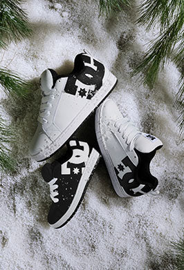 Black and white Court Graffik sneakers on a snowy background decorated with spruce branches