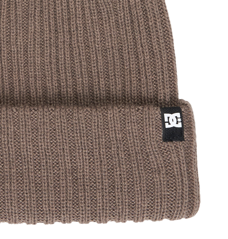 A close-up of the DC Shoes Fish N Destroy 2 beanie highlights its brown ribbed knit design and folded brim, crafted from recycled fibers for an eco-friendly appeal. This comfortable beanie features a small black and white DC Shoes logo tag on the brim.