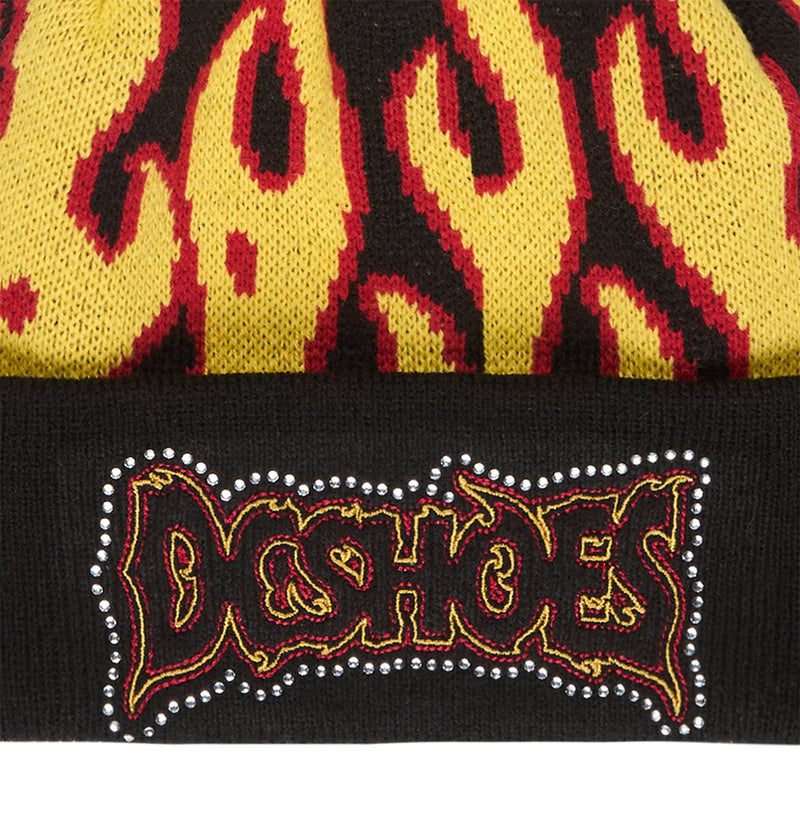 A close-up of the Burning Beanie by DC Shoes showcases its bold yellow and red flame pattern, accented with a DC SHOES patch outlined in small silver studs—making it the ultimate statement piece for fiery style.