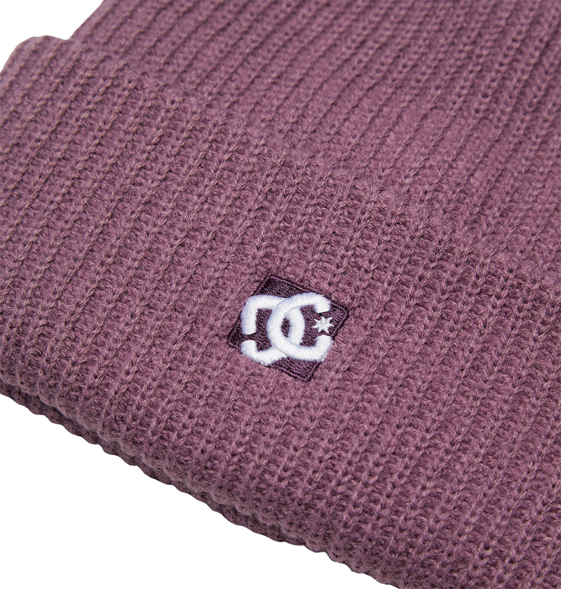 Close-up of a ribbed, mauve Lanai Beanie by DC Shoes, crafted from recycled fibers, featuring a folded brim and a stitched white logo patch near the edge.