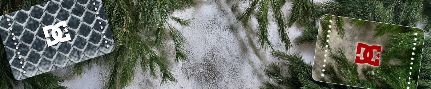 Two DC shoes gift cards with a frosted fence texture and a spruce branch texture on a snowy ground with evergreen trees in the background