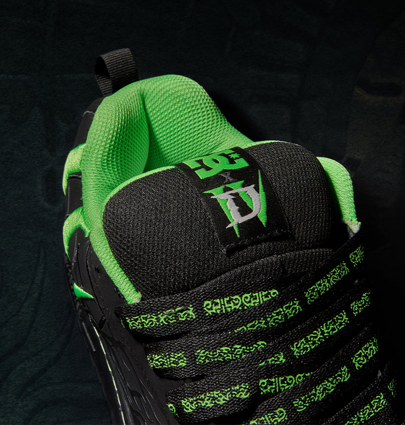 Close-up of a black Men’s Court Graffik x Diablo skate shoe featuring a bright green interior lining and laces patterned with green gothic-style text.