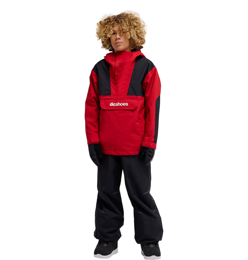 A young person with curly hair wears the DC Shoes DC-43 Youth Anorak—a red and black insulated snow jacket—paired with black gloves and black pants, standing against a plain white background.