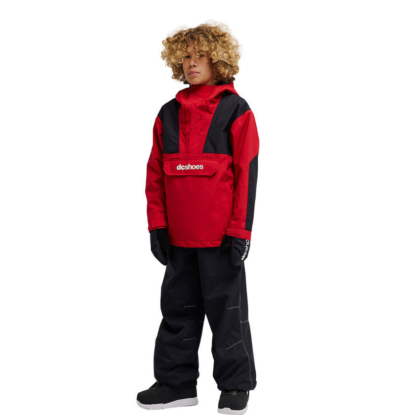 A child with curly hair wears a red and black jacket featuring breathable front protection, DC Shoes Trackstar Baggy Youth Pants in black, black gloves, and black sneakers, standing against a white background.