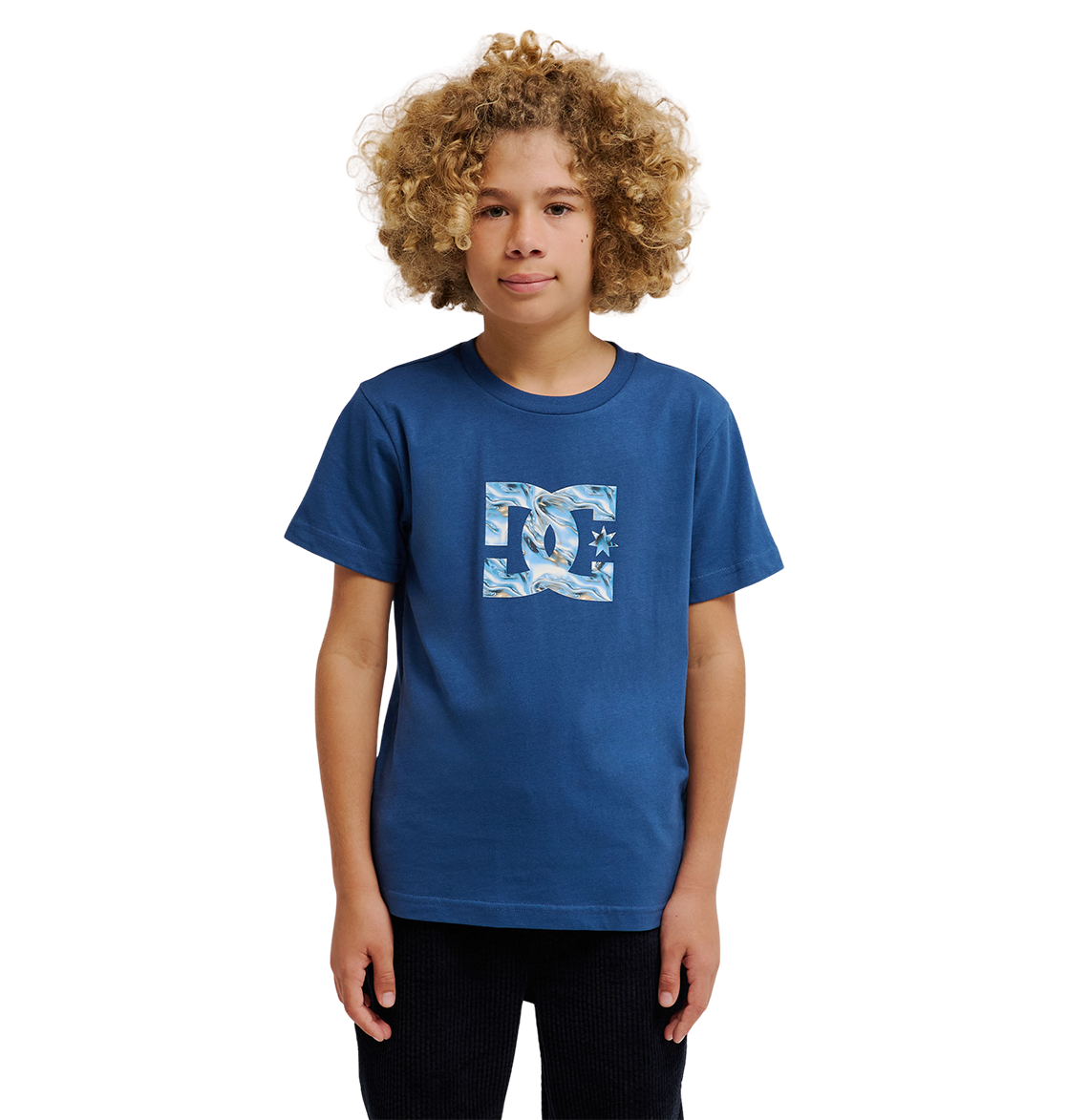 A child with curly blond hair faces forward against a plain white background, wearing the DC Shoes "DC Star Filled Tee Youth," a blue skate t-shirt featuring bold DC star artwork.