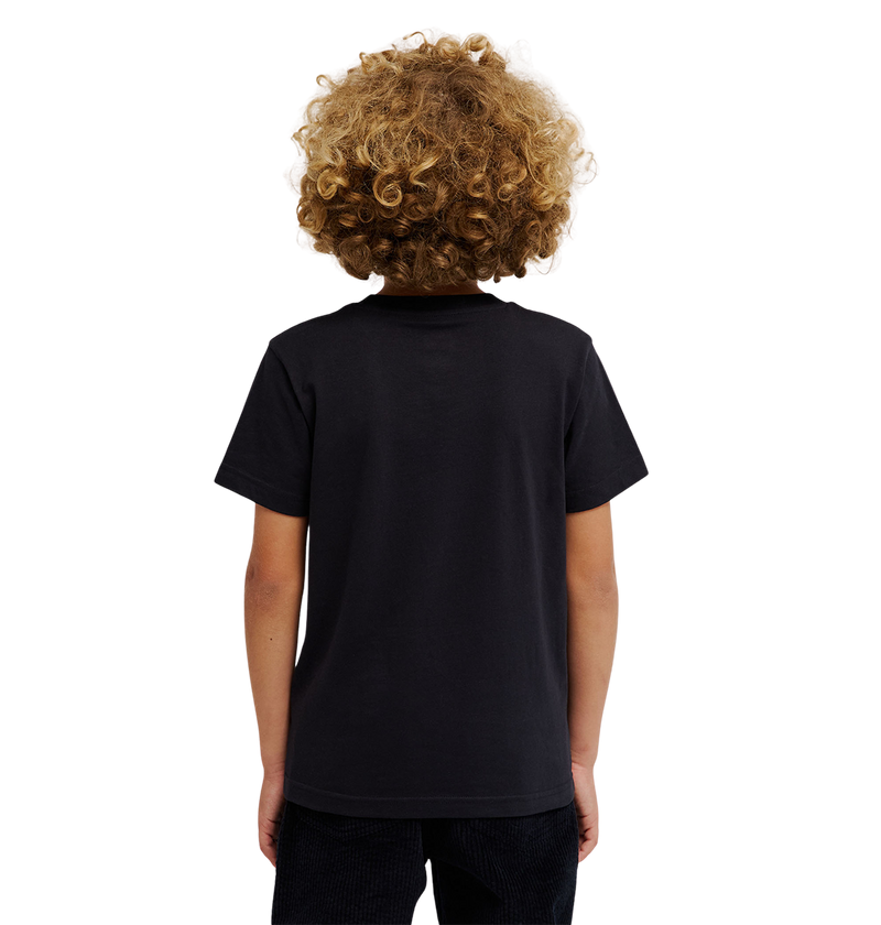 A child with curly blonde hair is standing facing away, wearing a DC Shoes DC Star Filled Tee Youth in black and black pants against a light background.