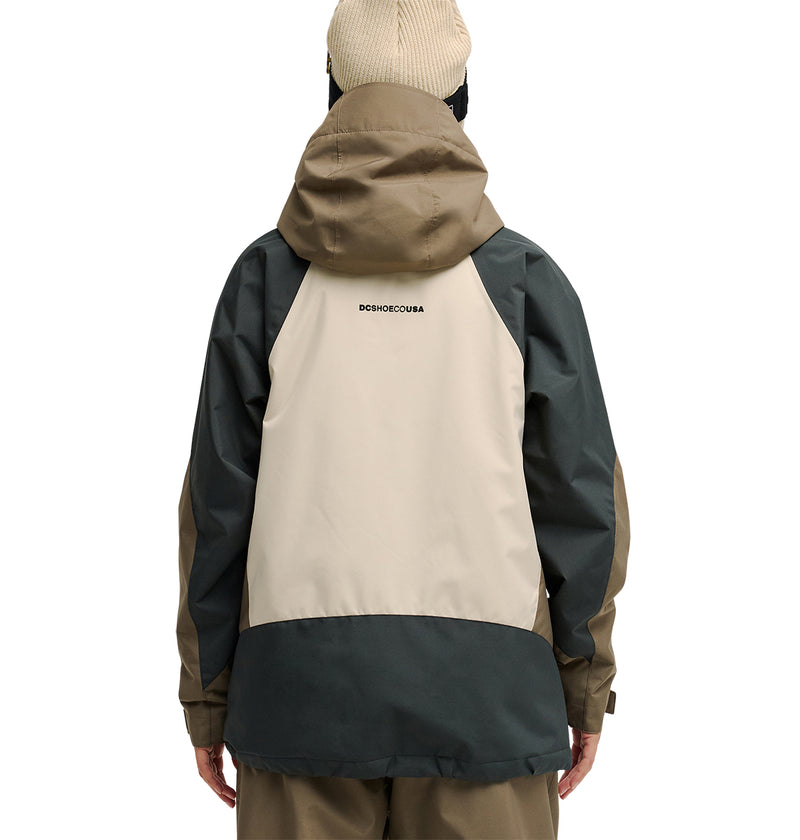 A person seen from the back wearing the DC Shoes Everfrost Jacket—a tan and dark green hooded waterproof jacket with “DC SHOES CO USA” printed on the upper back—paired with a beige beanie.