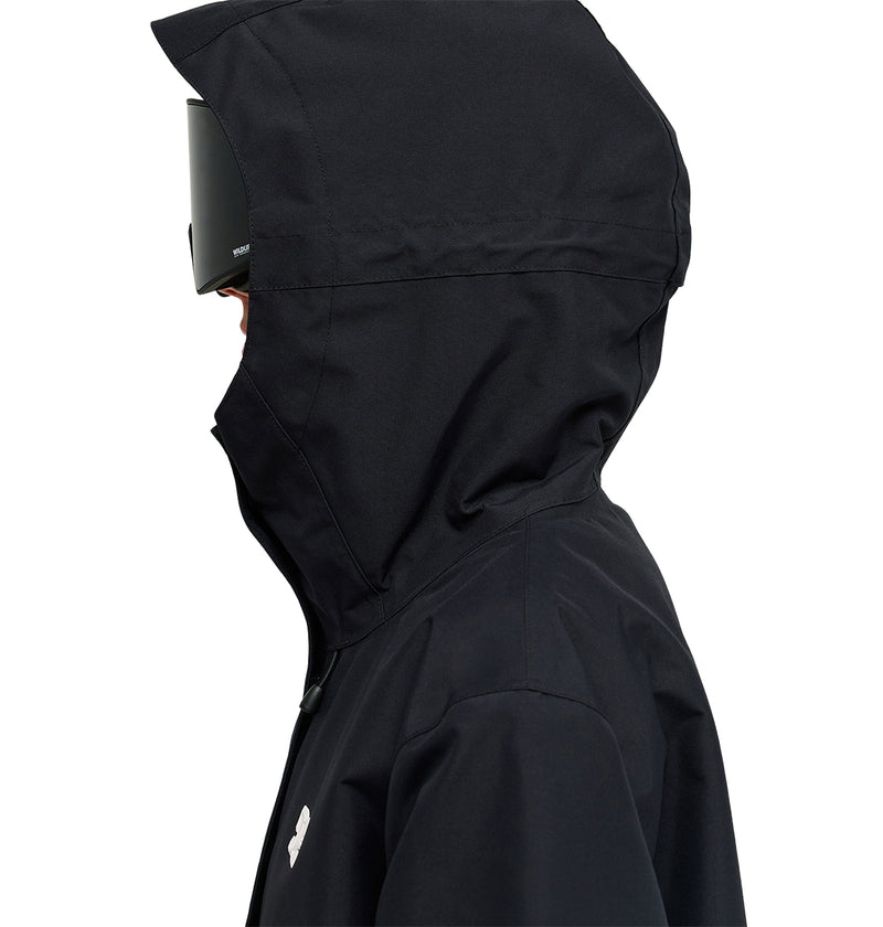 A person is seen facing left, wearing the DC Shoes Cruiser Jacket—a black insulated jacket with a hood and black visor—against a white background, their face mostly obscured.