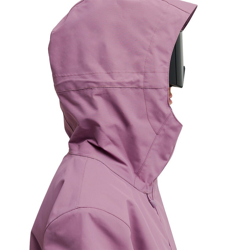 A person in side profile is wearing the DC Shoes Cruiser Jacket, a pink insulated jacket with a hood, along with large black goggles that cover most of their face, set against a white background.